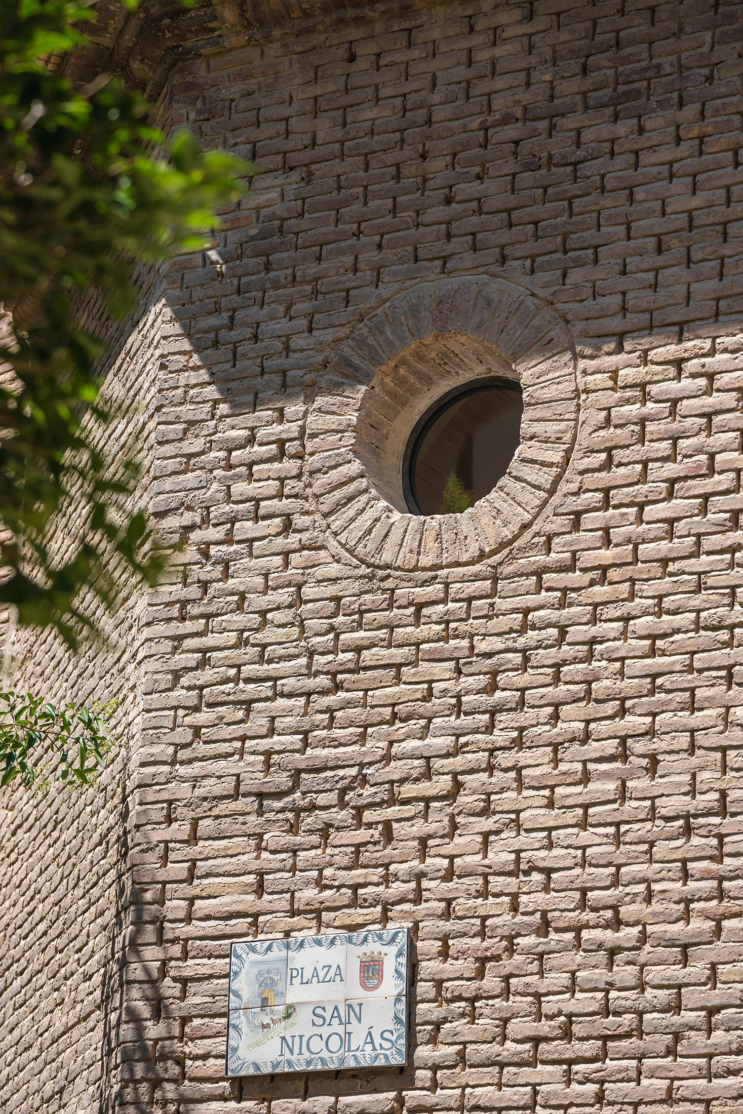 Detalle de la fachada exterior de ladrillo restaurado con un pequeño óculo circular